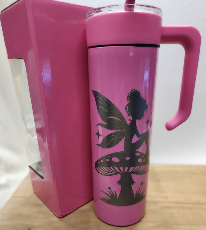 Whimsy meets legacy in this soft pink tribute tumbler, engraved with a bold fairy silhouette perched on a mushroom beneath a scatter of stars. Packaged in a matching pink kettle-style box, this set delivers more than hydration—it delivers a moment. Designed for dreamers, crafted for storytellers, and built to honor the magic in everyday resilience.
• 	20oz insulated tumbler with handle, lid, and straw
• 	Laser-engraved fairy design with mushroom and star accents
• 	Includes matching pink kettle-style gift b